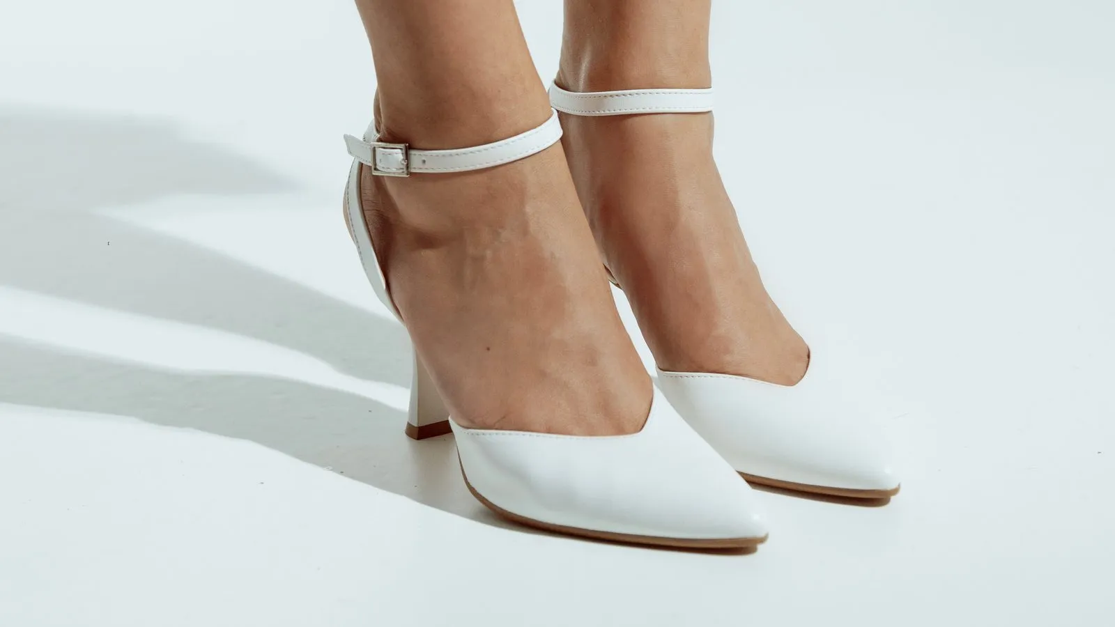 Décolleté da sposa Elena in bianco ai piedi, con il cinturino alla caviglia allacciato: la calzata vista di fronte
