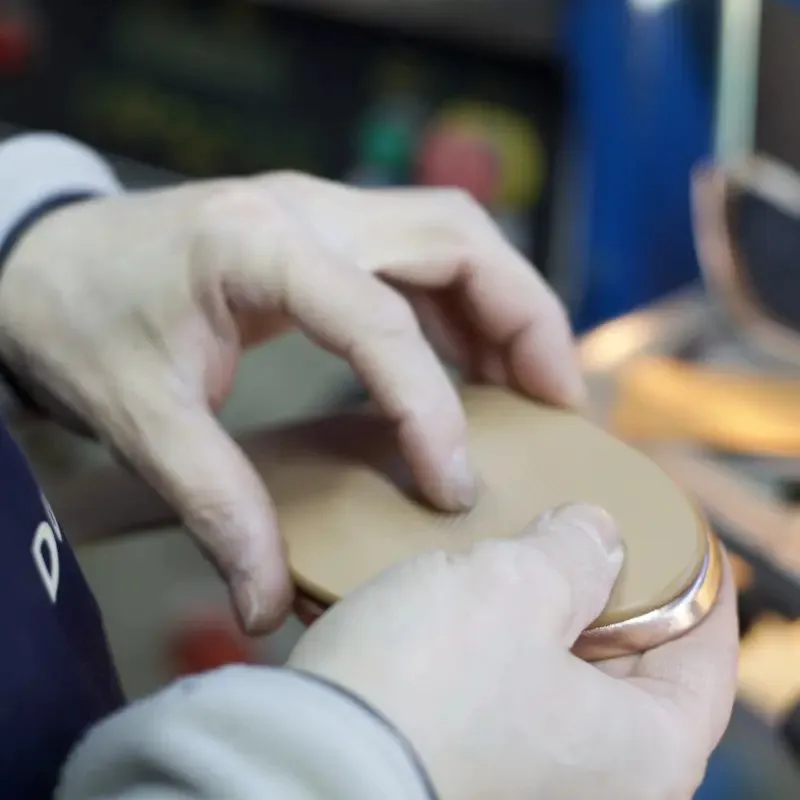 Le mani di un artigiano montano il sottopiede sulla forma, al banco del laboratorio di Trani