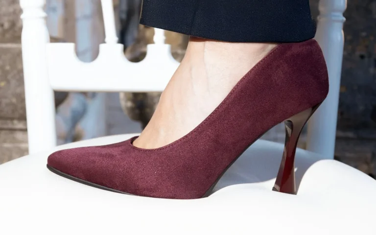 Décolleté in camoscio Perla Bordeaux appoggiata su una sedia bianca