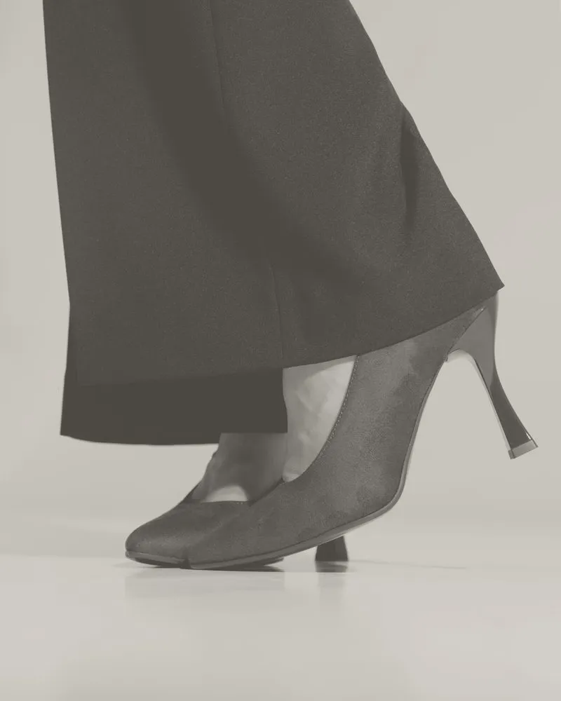 Profilo di un tacco a rocchetto sotto un pantalone nero: foto in bianco e nero