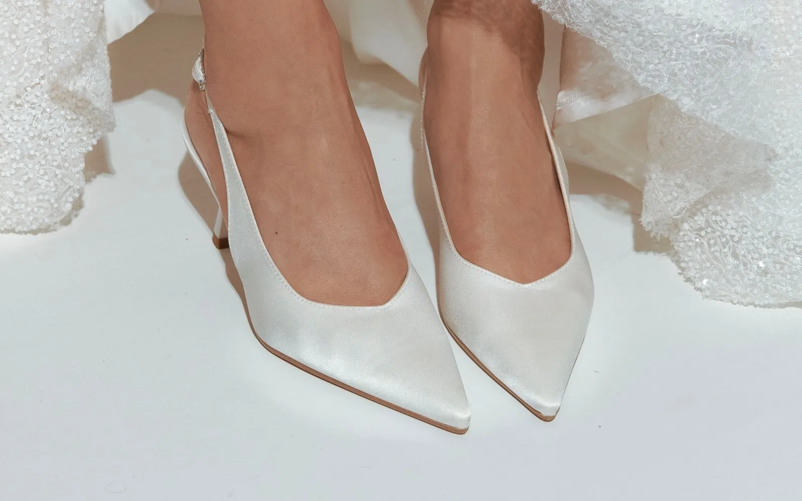 Scarpe da sposa che spuntano dall'orlo di un abito ricamato