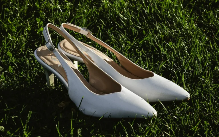 Un paio di slingback da sposa appoggiate sull'erba, in luce radente